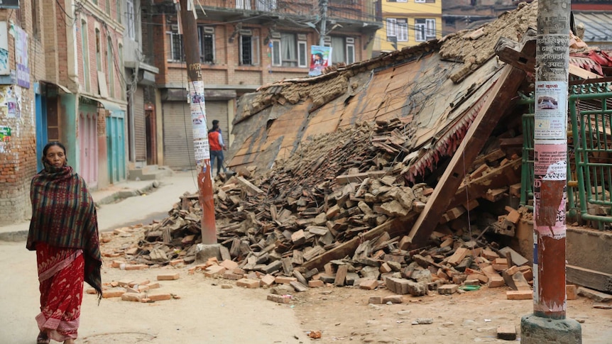 Woman walks by collapsed buildings in Nepal