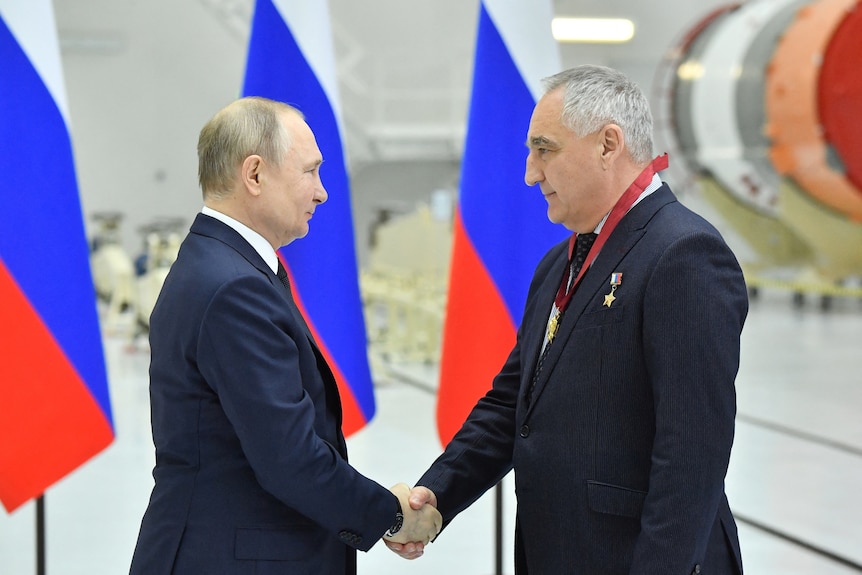 Putin and Skvortsov shake hands facing each other while smiling.