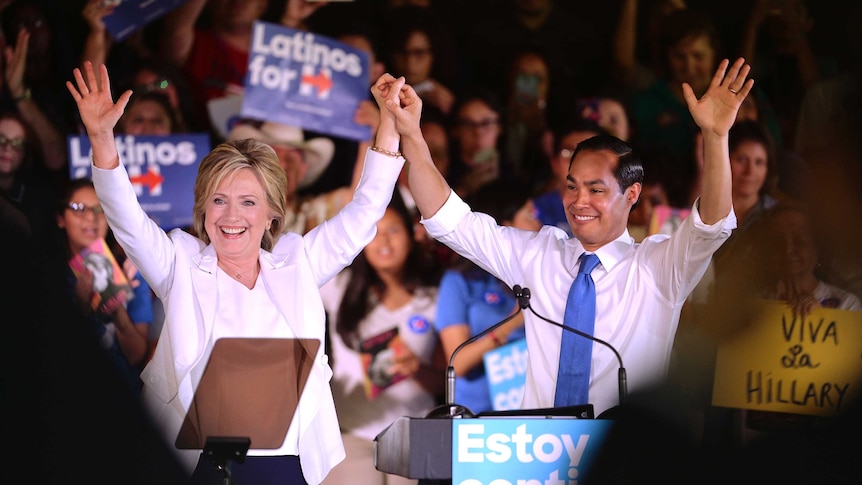 Julian Castro and Hillary Clinton hold their hands together in the air and wave at the crowd