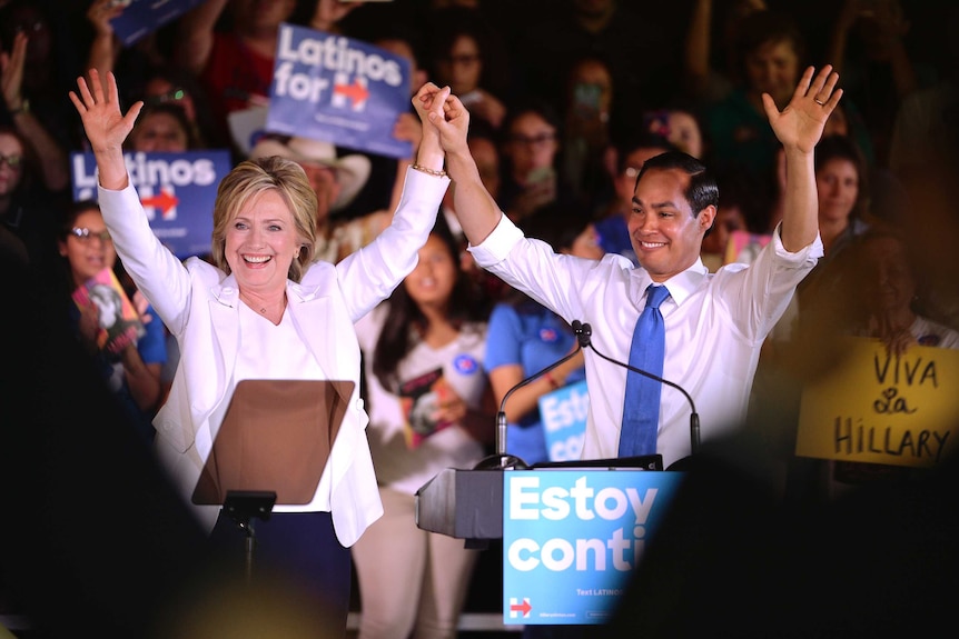 Julian Castro and Hillary Clinton hold their hands together in the air and wave at the crowd