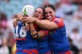 Three NRLW players embrace in a hug, one crying, after winning the premiership