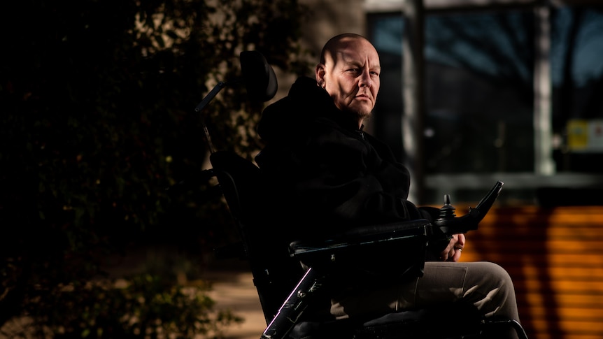 A man in dark clothing sitting in a wheelchair