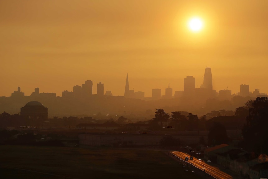 A wide-shot of San Francisco shows the skyline turned orange from nearby fires.
