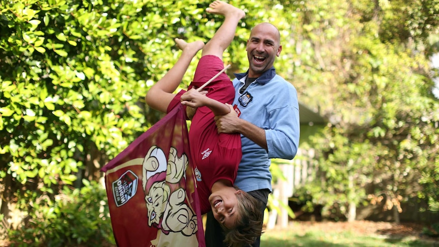 Blues supporter Craig Vignon and holds his 11-year-old son Rio upside down.