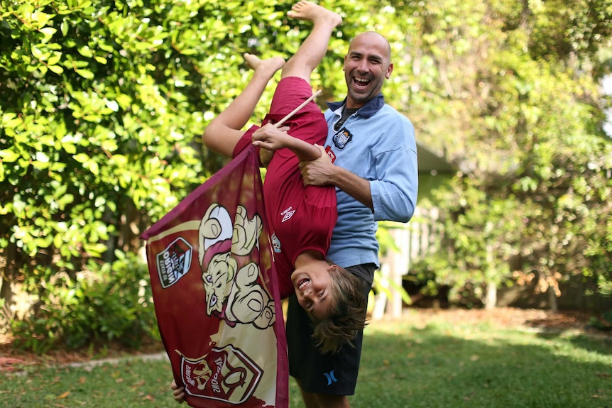 Blues supporter Craig Vignon and holds his 11-year-old son Rio upside down.