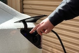 A man's hand charging a while electic car. 