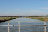 A large irrigation channel with green grass on banks on either side
