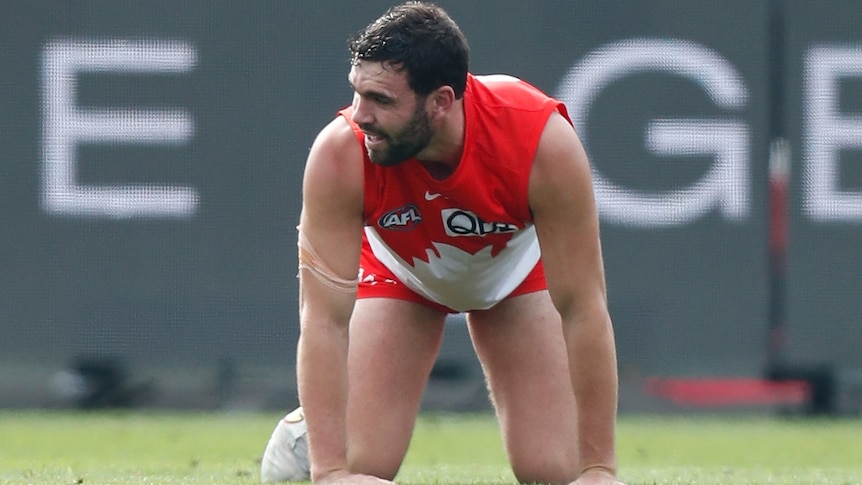 A Sydney Swans AFL player on his hands and knees following a collision with another player.