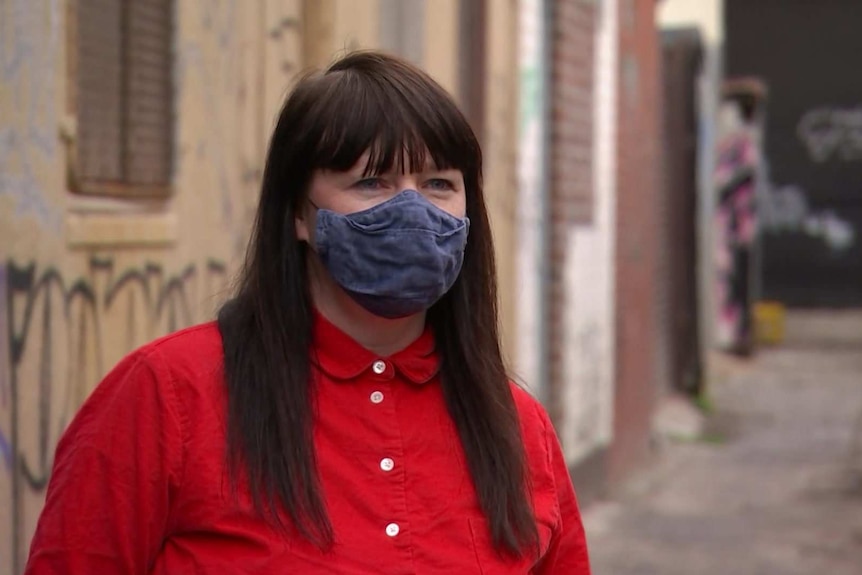 A woman wearing a red shirt and a face mask.