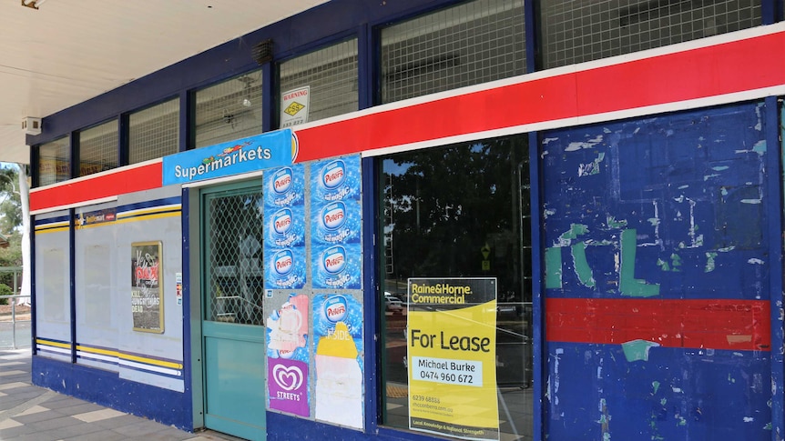 A close-up of a supermarket which is closed, with a 'for lease' sign on window.