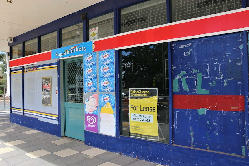 A close-up of a supermarket which is closed, with a 'for lease' sign on window.