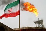 A gas flare on an oil production platform in the Soroush oil fields is seen alongside an Iranian flag in the Persian Gulf, Iran