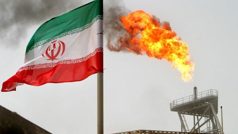 A gas flare on an oil production platform in the Soroush oil fields is seen alongside an Iranian flag in the Persian Gulf, Iran