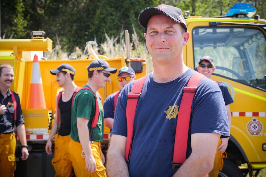 Robin Gaytenbeek with has arms crossed, standing in front of a fire truck and some of his crew.