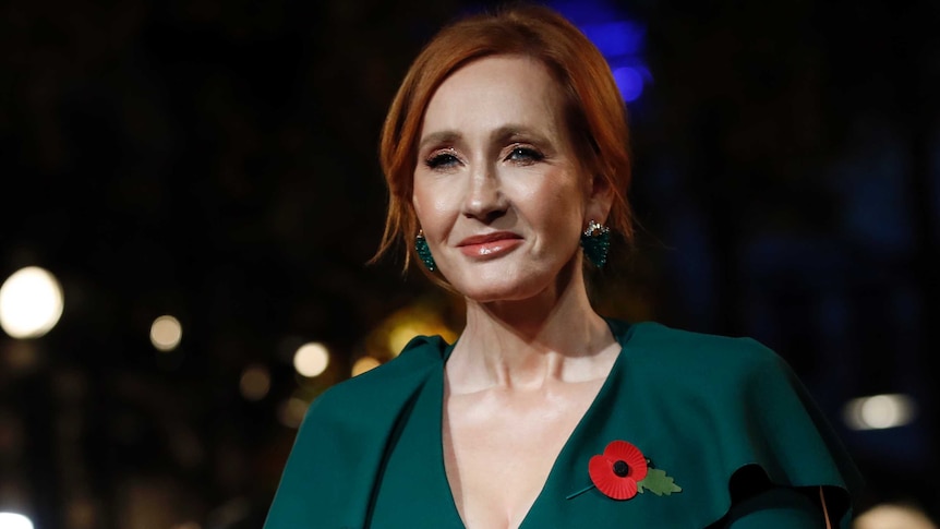 JK Rowling with red hair and a poppy on her green blouse.