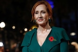 JK Rowling with red hair and a poppy on her green blouse.