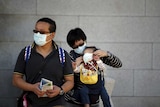 A Chinese tourist puts a mask on her child's face to prevent contracting MERS