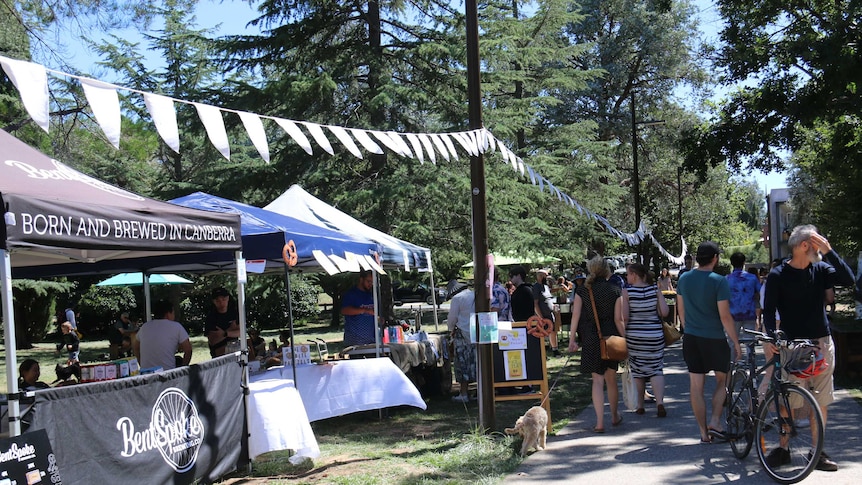 People stroll by a row of stalls offering local produce.