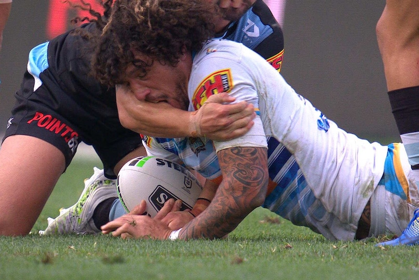 A Gold Coast Titans NRL player makes contact with the right forearm of a Cronulla opponent with his mouth while being tackled.