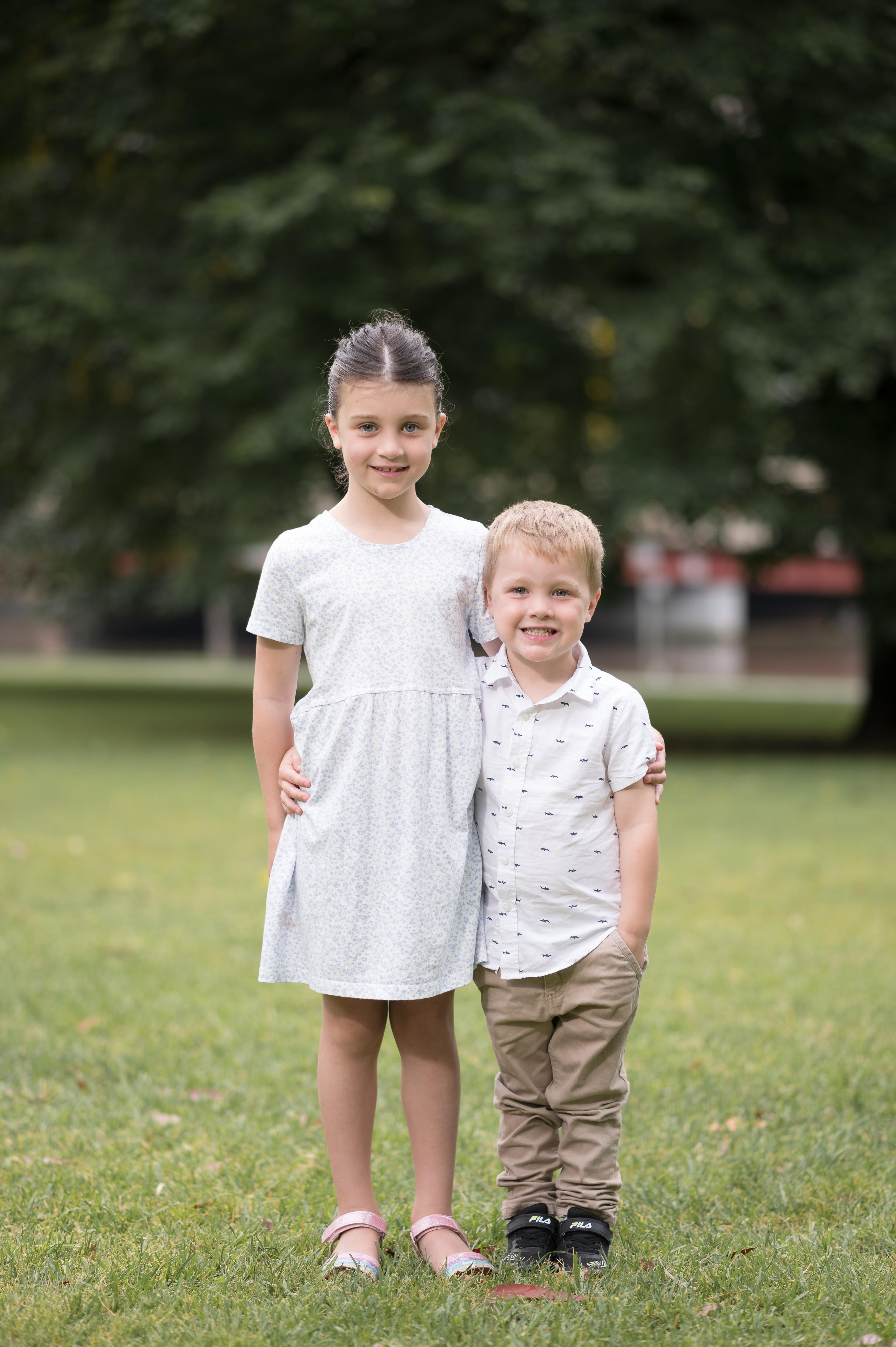 Four year old Chris smiling for a photo with his older sister 