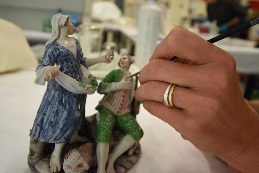 A hand painting a porcelain sculpture