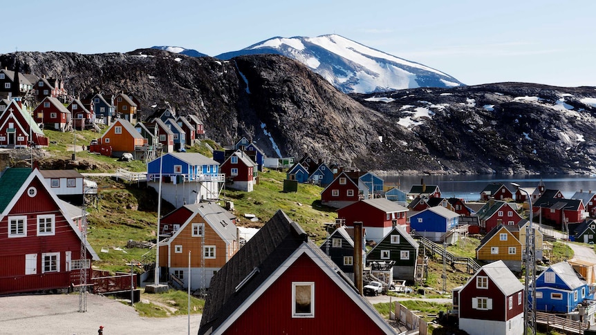 People walk through a neighbourhood in Greenland overlooking an icy mountain vista