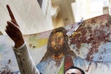 Egyptian Christians hold a blood-stained portrait of Jesus Christ