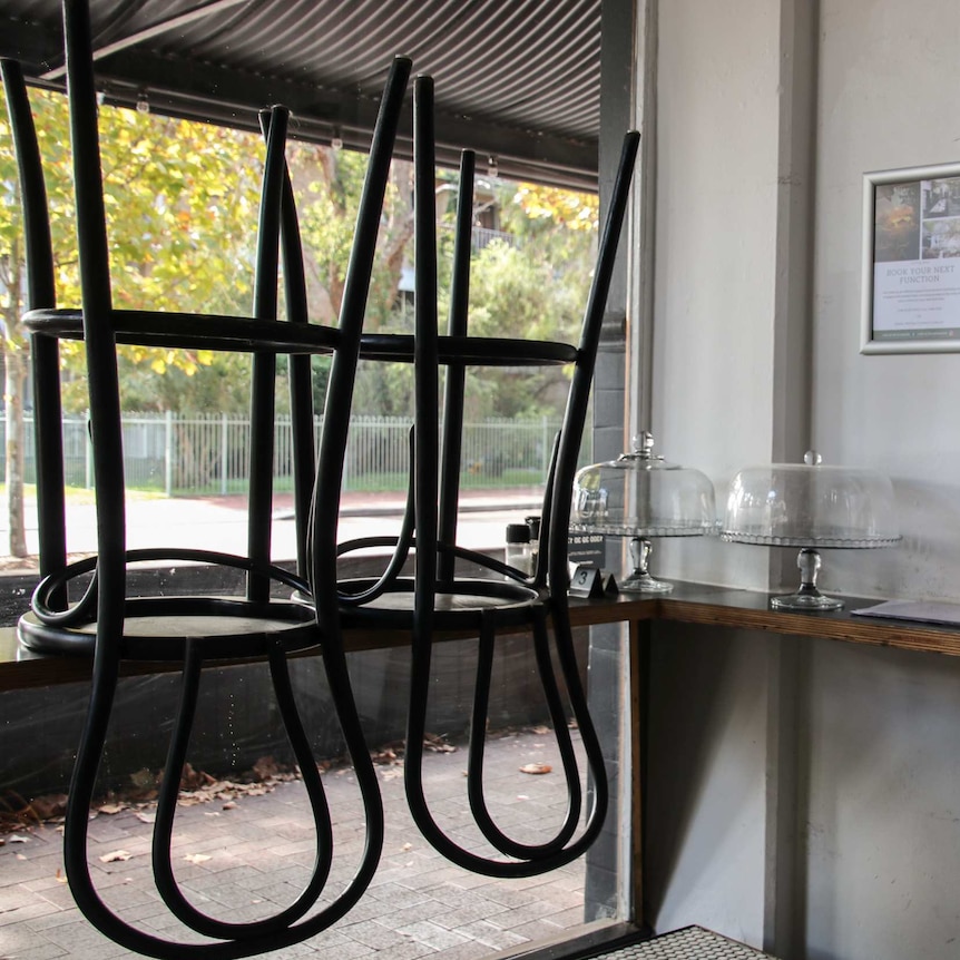 A restaurant window with chairs stacked on a table