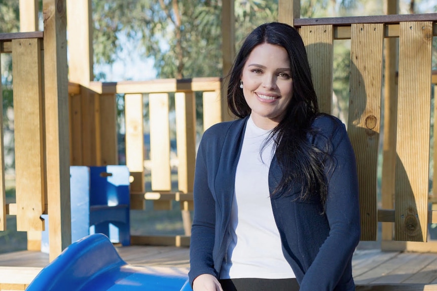 a young woman in a dark suit and long black hair, smiling