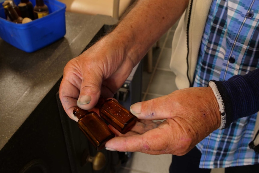 Small amber glass bottles being held in a man's hands.