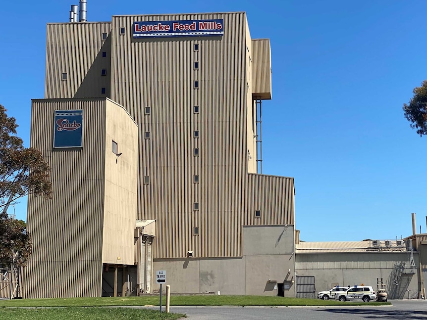 A tall cream building with very small windows with police cars next to it