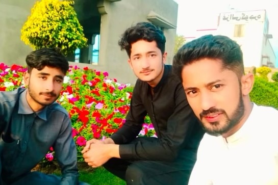 three young brothers sitting in front of a rose bush outdoors