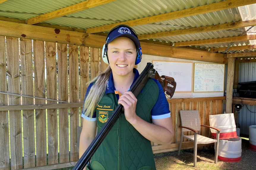A woman looking at the camera holding a competition gun.