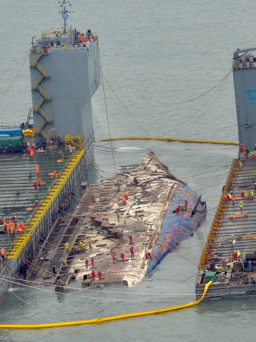 Workers prepare to lift the sunken Sewol ferry, centre, in waters off Jindo, South Korea, Thursday, March 23, 2017.