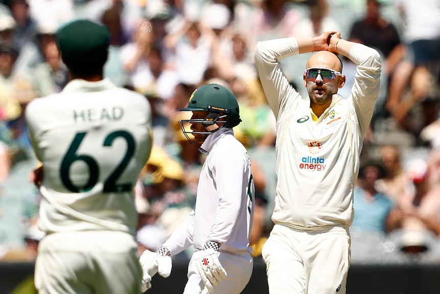 Nathan Lyon stands with his head in his hands