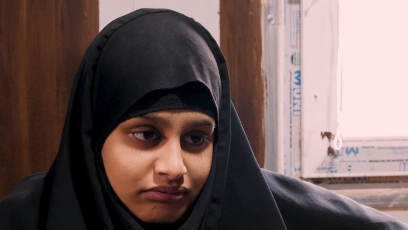 A woman wearing Islamic religious attire looks away from the camera during an interview.