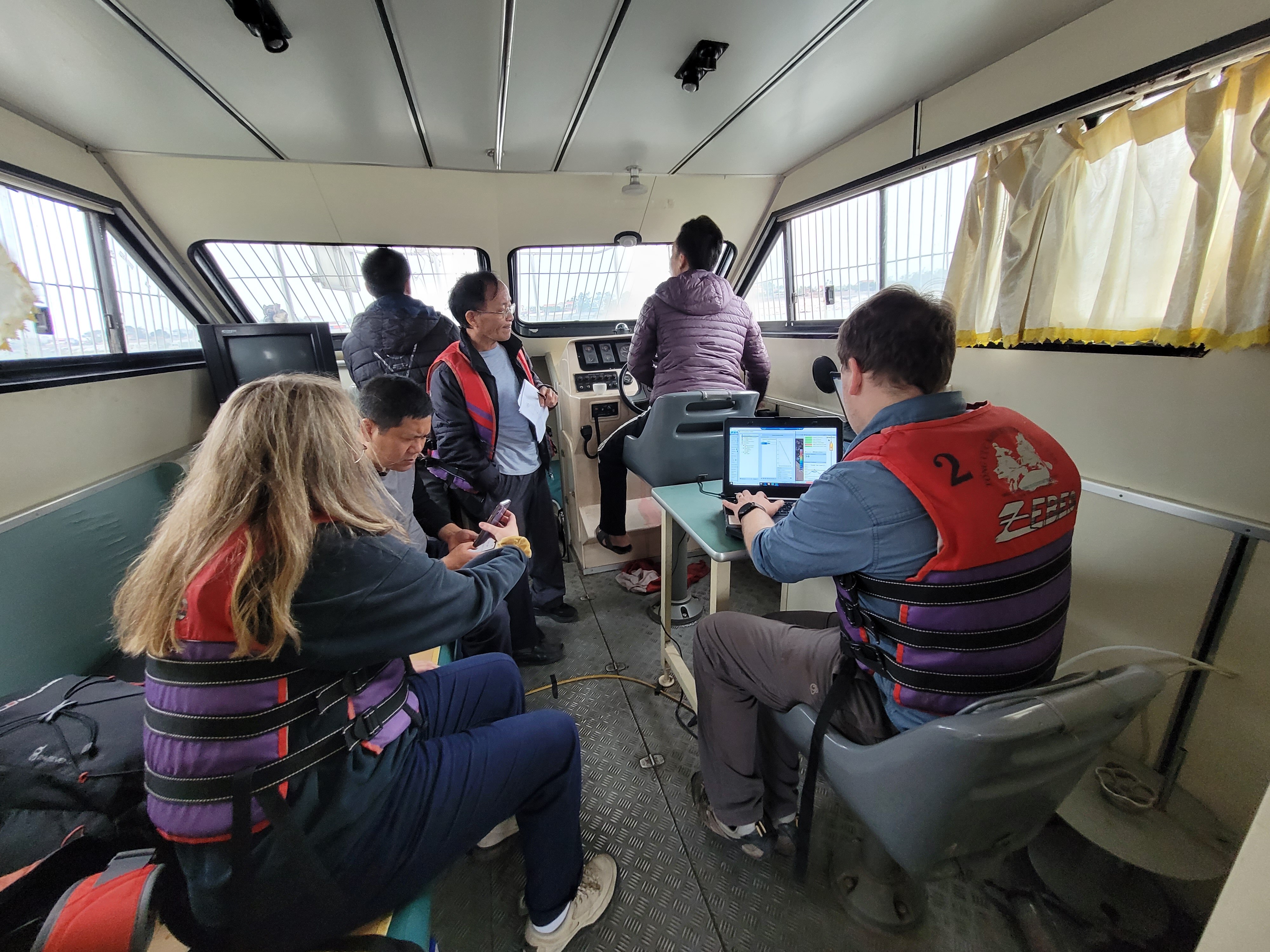 A group of young researchers, travelling on a boat on the Red River Delta.