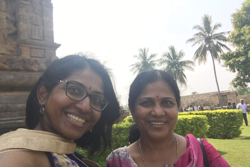 The author and her mother pose for a holiday photo in front of an ancient temple in India.