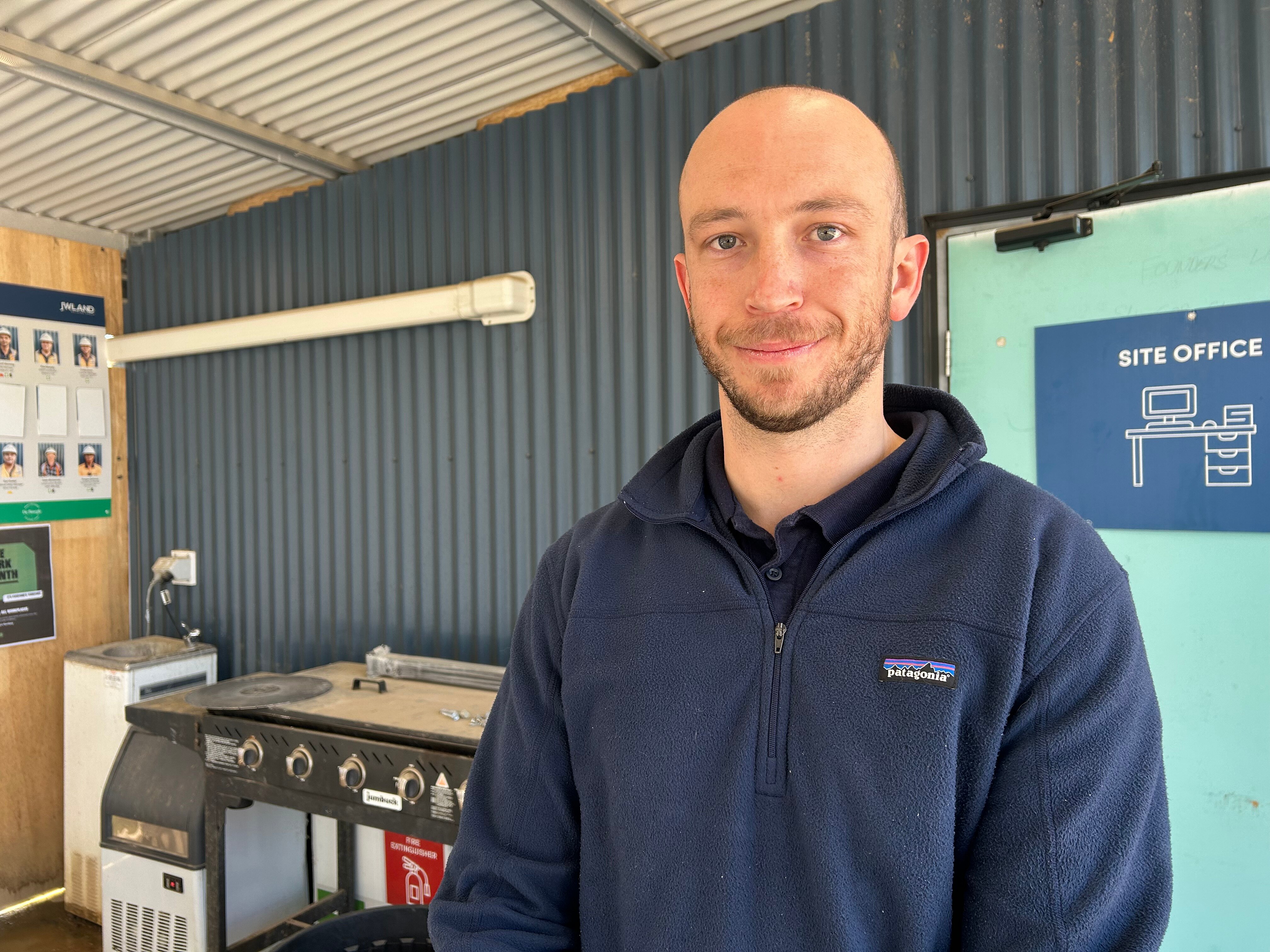 A bald man in a blue jumper smiles.