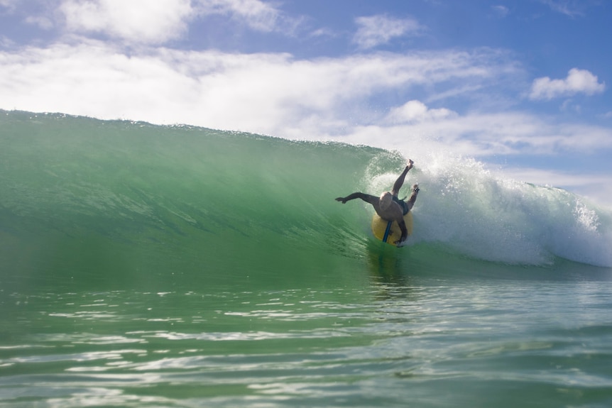 Man catching a steep wave, lying on a surf board