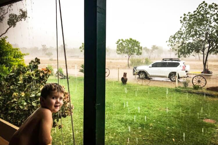 Young boy leans on verandah rail during deluge at home in drought-stricken Stawellton Station.