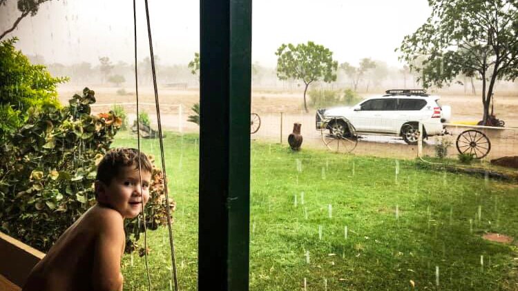 Young boy leans on verandah rail during deluge at home in drought-stricken Stawellton Station.