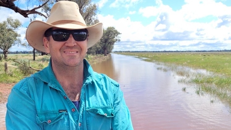 Farmer standing with wet paddocks in the background