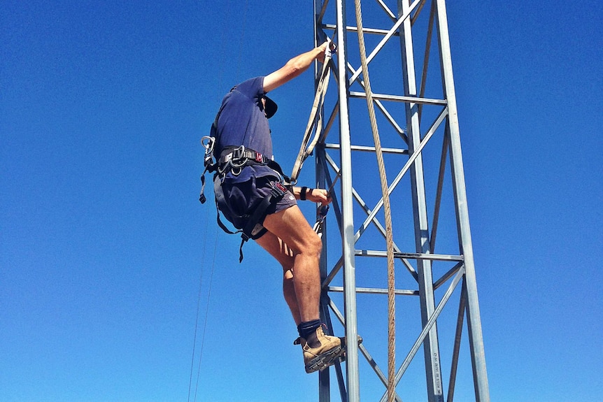 A man climbs an internet tower on a farm