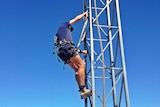 A man climbs an internet tower on a farm