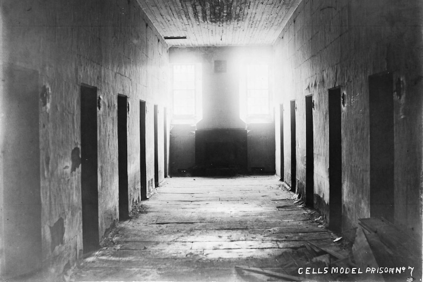 Black and white photo of dark building with five cells on each site