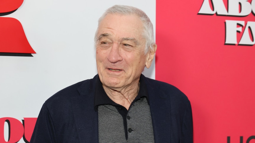 Robert De Niro in front of a red press wall background