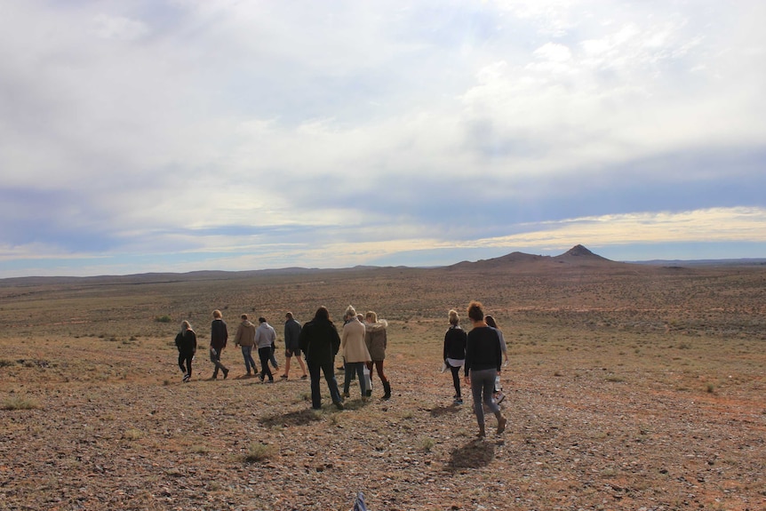 A group of beginning teachers walk among the Pinnacles in Broken Hill to the left with their backs towards the camera
