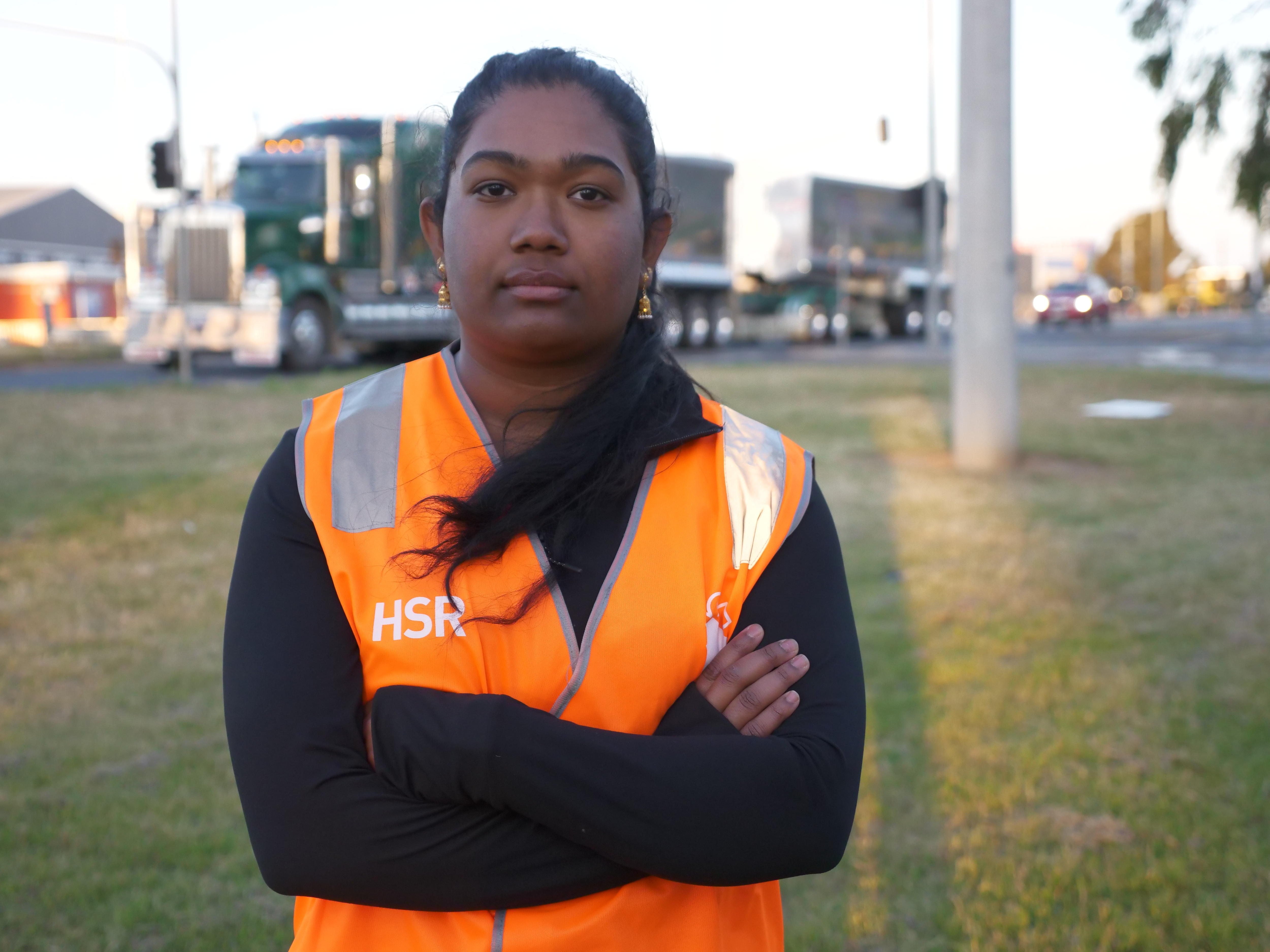 A woman wearing an orange high vis jacket with her arms crossed