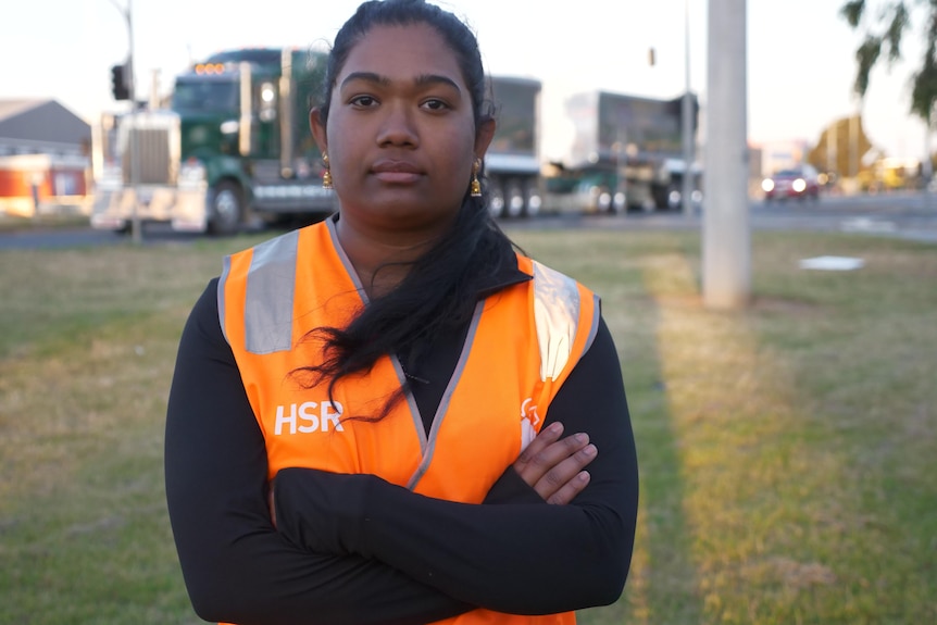 A woman wearing an orange high vis jacket with her arms crossed